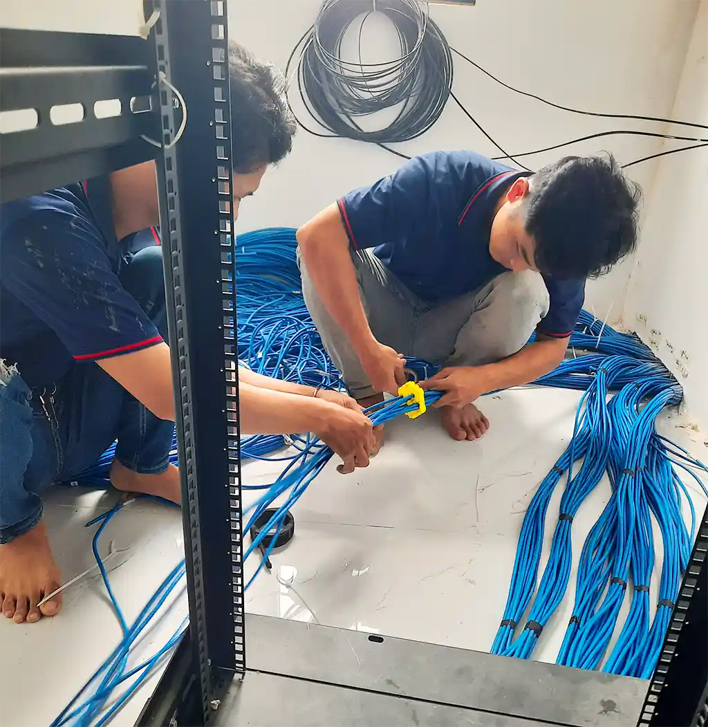 Thi công hạ tầng mạng chuyên nghiệp cho doanh nghiệp – Giải pháp tối ưu hệ thống CNTT 3 Kỹ thuật viên đang phân luồng, bó gọn dây cáp mạng bằng dụng cụ chuyên dụng để đảm bảo tính thẩm mỹ và dễ bảo trì.